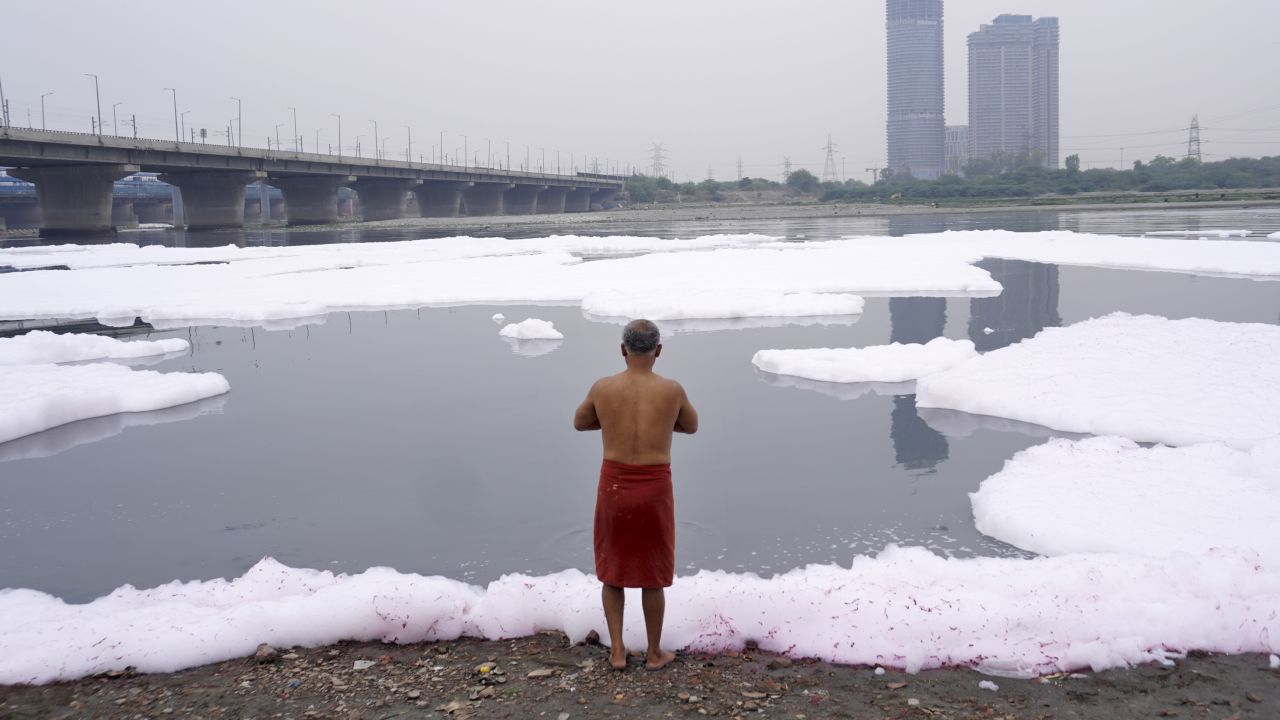 A man performs rituals in the Yamuna River, filled with toxic foam from industrial and domestic wastewater, in New Delhi, India, on March 19, 2023. 
