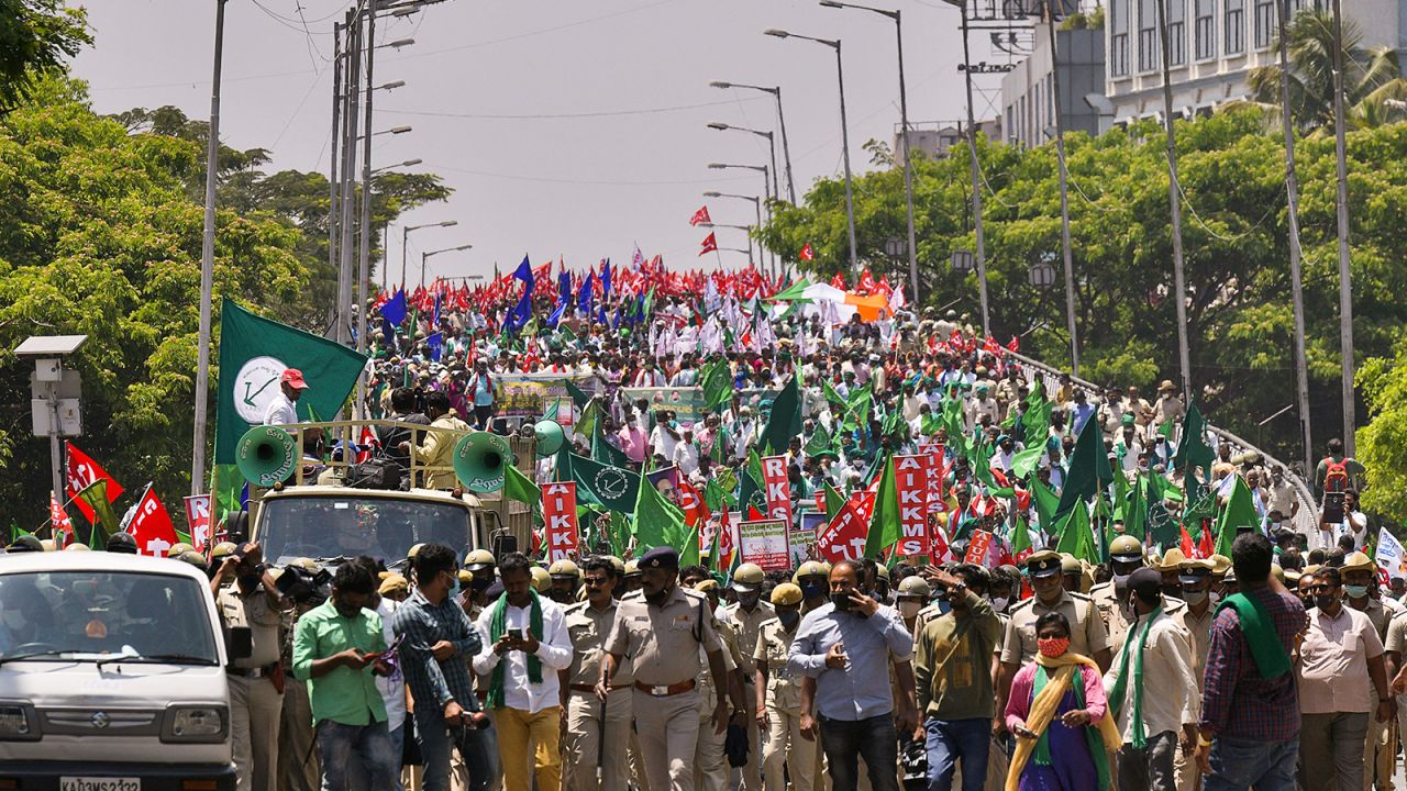 Police march in front of farmers during a protest against the central government's proposed agricultural reforms in Bangalore on March 22, 2021. 