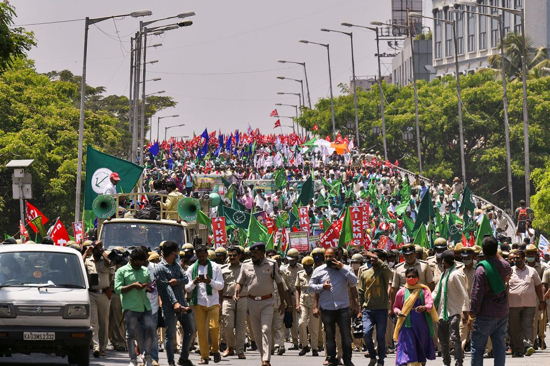 Police march in front of farmers during a protest against the central government's proposed agricultural reforms in Bangalore on March 22, 2021. 