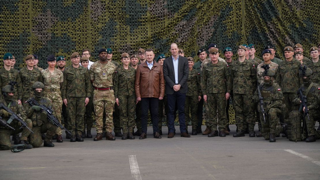 Prince William and Polish Deputy Prime Minister and Minister of Defence Mariusz Blaszczak (center left) pose for a group photo with British and Polish troops.