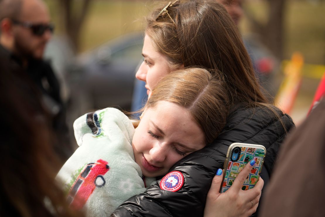 Two onlookers hug after a school shooting at East High School on Wednesday in Denver. 