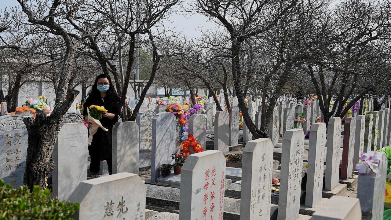 A woman carries flowers as she visits the Babaoshan People's Cemetery in Beijing on April 4, 2022