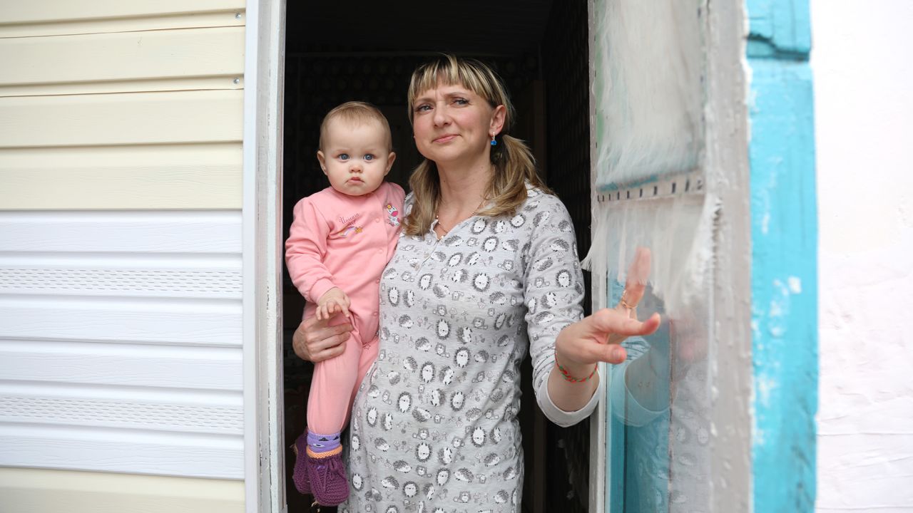 Tetiana Pavelko, holding Kira, opens the door as the sound of artillery shells echoes around.