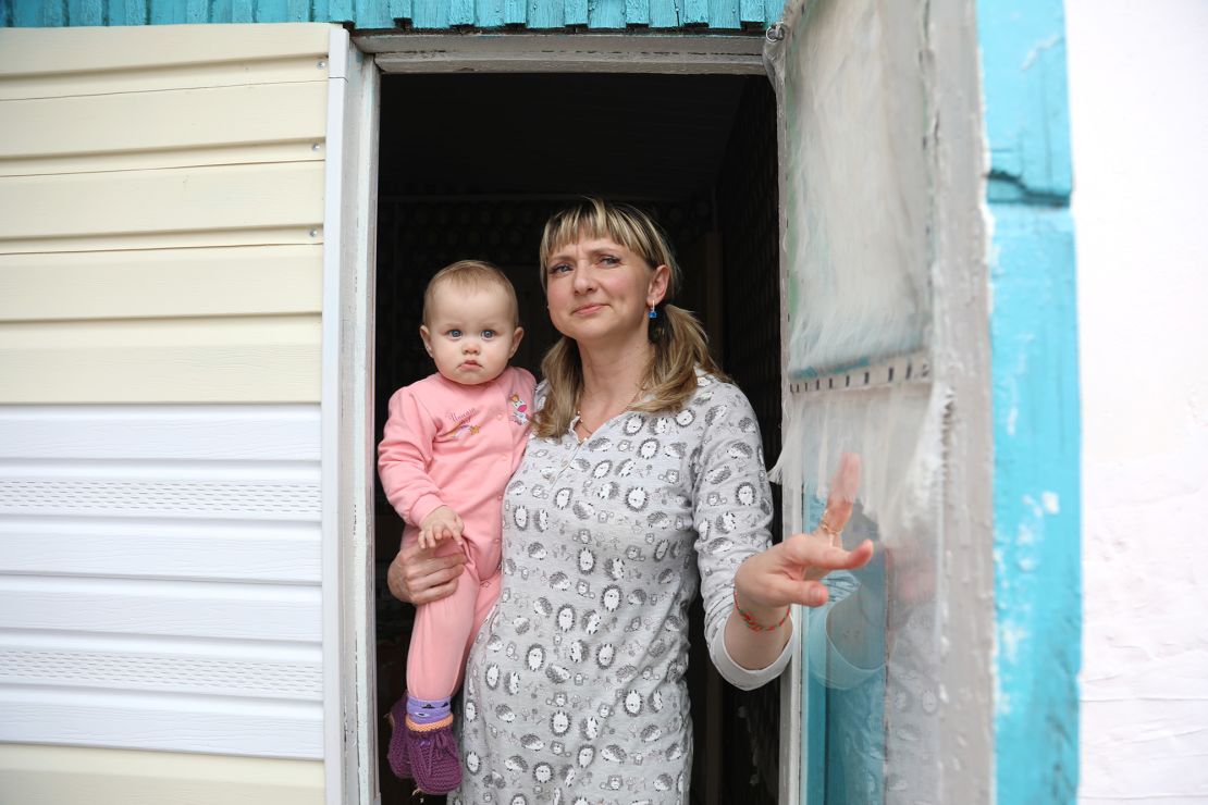 Tetiana Pavelko, holding Kira, opens the door as the sound of artillery shells echoes around.
