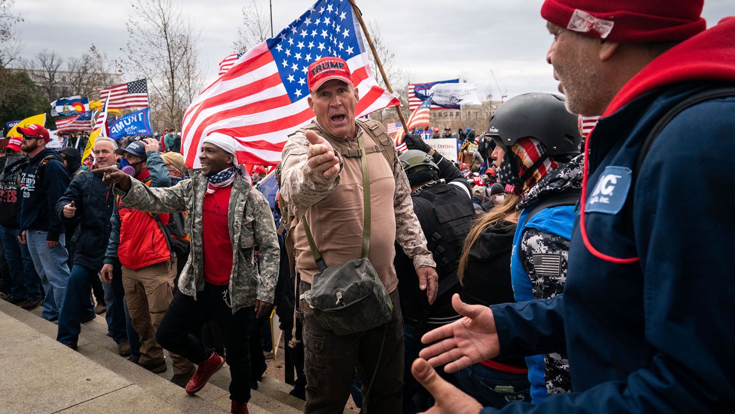 Ray Epps, in the red Trump hat, center, gestures to others as people gather on the West Front of the U.S. Capitol on Wednesday, Jan. 6, 2021.