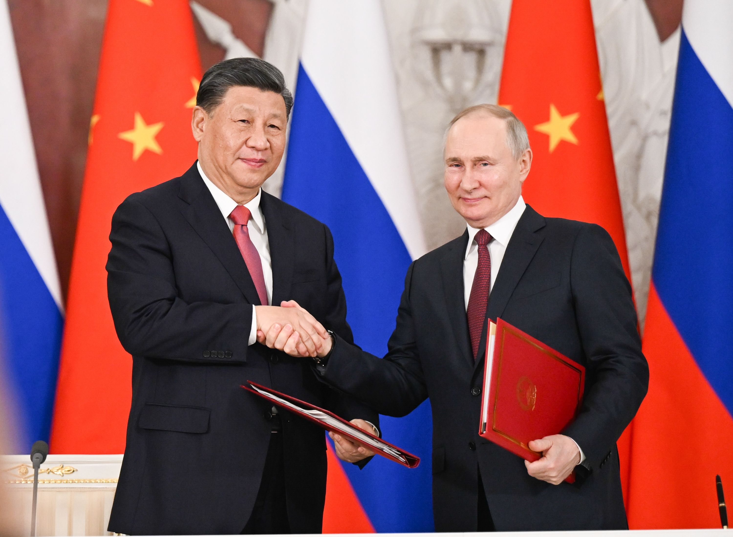 Xi Jinping and Vladimir Putin shaking hands during a meeting in Moscow.