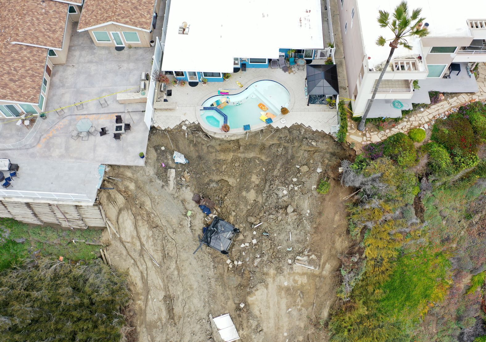 A swimming pool sits on the edge of a cliff Thursday, March 16, following a landslide in San Clemente, California. As storms have pummeled the state in quick succession since late December, more soil has become oversaturated and <a href="index.php?page=&url=https%3A%2F%2Fwww.cnn.com%2F2023%2F03%2F21%2Fus%2Fcalifornia-weather-atmospheric-river-drought-climate%2Findex.html" target="_blank">vulnerable to flooding and mudslides</a>.