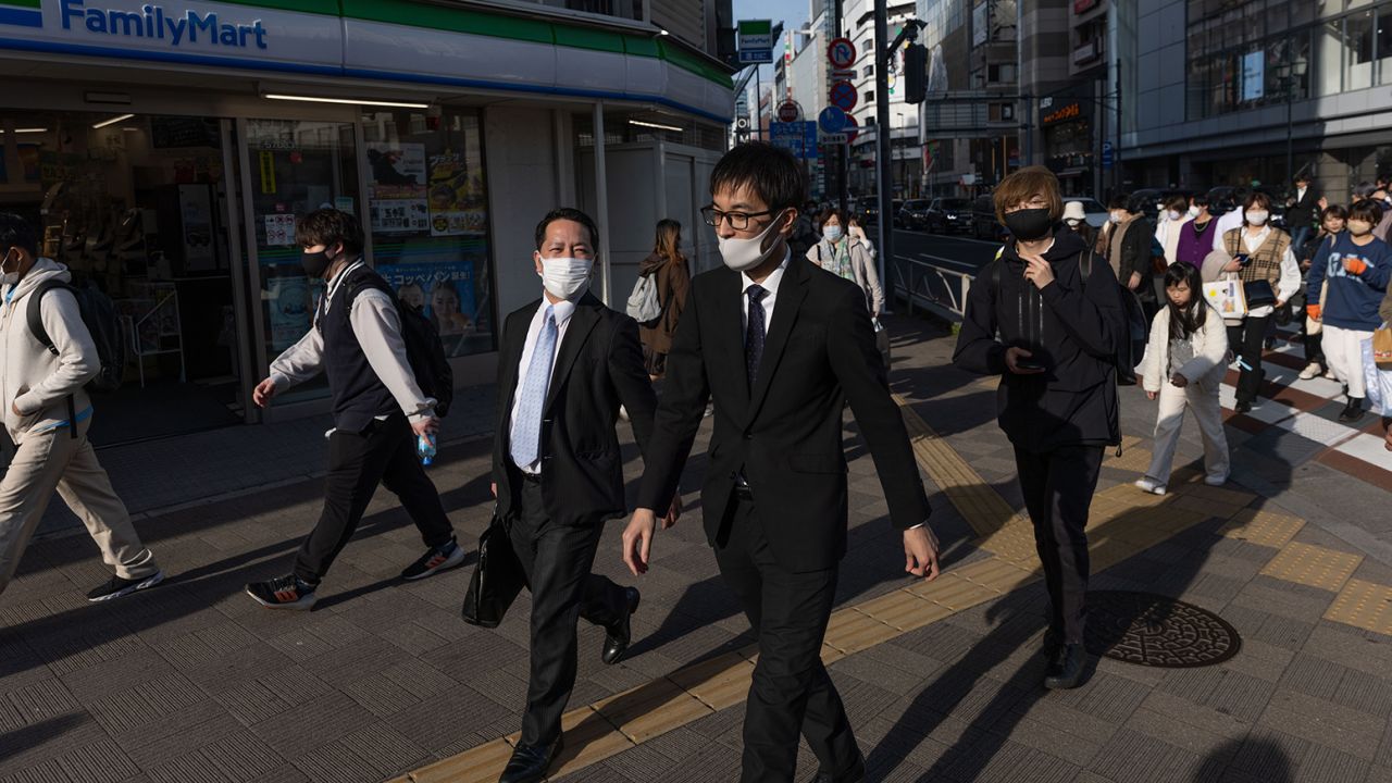 Businessmen walk towards Shinjuku station in Tokyo on March 16, 2023.