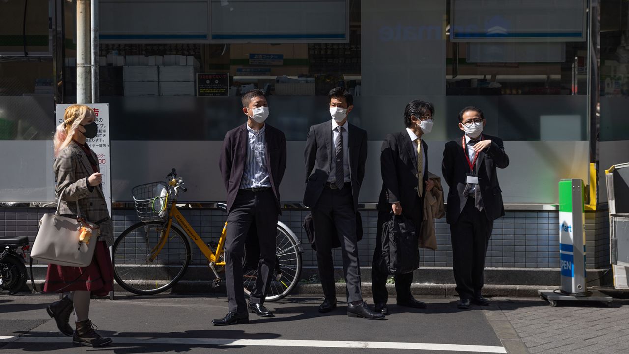 Businessmen in front of a convenience store in Ikebukuro, Tokyo, on March 16, 2023.