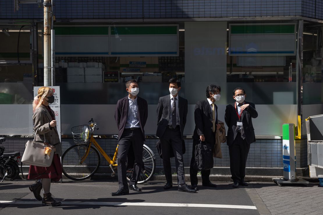 Businessmen in front of a convenience store in Ikebukuro, Tokyo, on March 16, 2023.