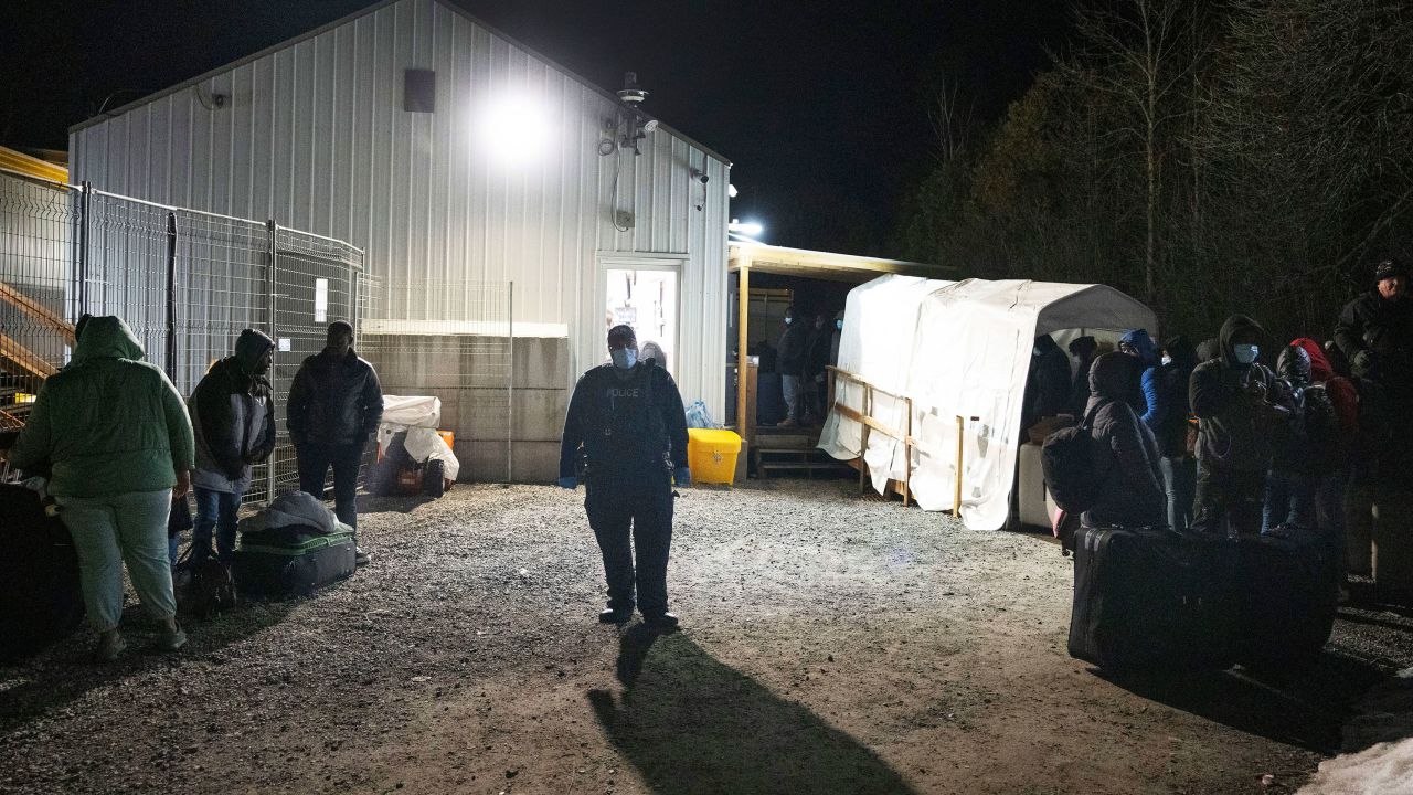A Royal Canadian Mounted Police officer pulls a family of asylum-seekers, left, aside after they crossed the border just after the midnight deadline at Roxham Road from New York into Canada, early Saturday, March 25, 2023, in Champlain, N.Y.