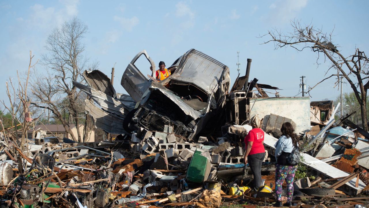 KeUntey Ousley tries to salvage what he can from his mother's boyfriend's vehicle, as his mother LaShata Ousley and his girlfriend Mikita Davis watch, after a tornado cut through their town the night before in Rolling Fork, Mississippi, March 25, 2023.  