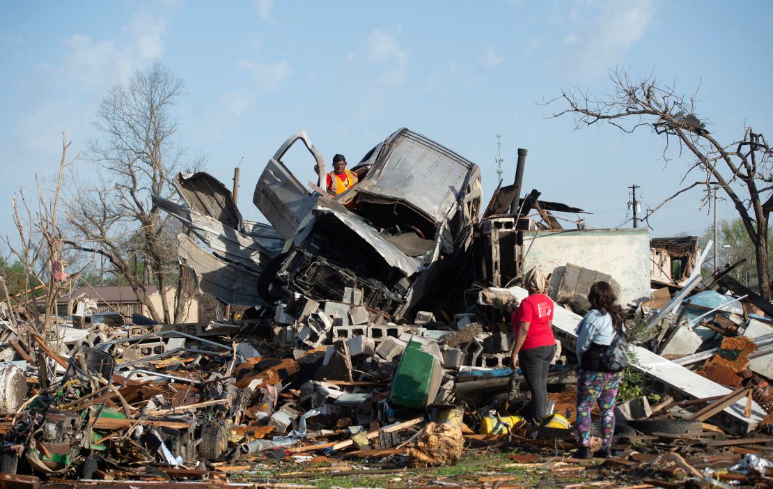 KeUntey Ousley tries to salvage belongings from his mother's boyfriend's vehicle as his mother LaShata Ousley and his girlfriend Mikita Davis watch in Rolling Fork, Mississippi.