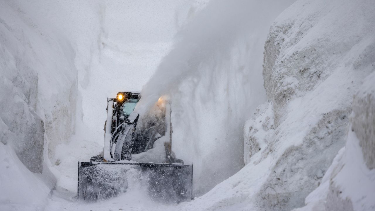  A tractor blows snow from a street that is walled in by snow as it continues to deepen in the first days of spring on March 21, in Mammoth Lakes, California. 