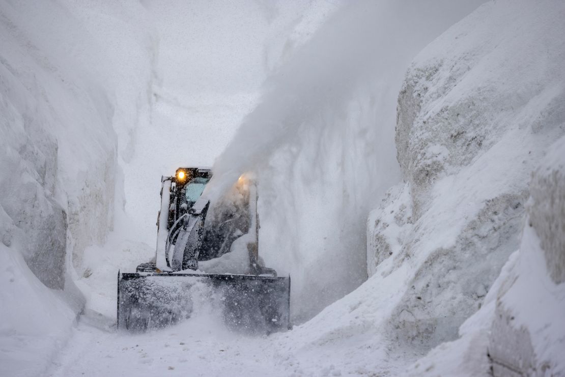  A tractor blows snow from a street that is walled in by snow as it continues to deepen in the first days of spring on March 21, in Mammoth Lakes, California. 