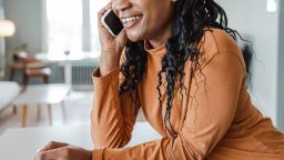 Photo of a young African-American woman smiling while talking on the phone at home