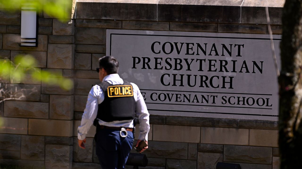 A police officer walks by an entrance to The Covenant School after a shooting in Nashville, Tenn. on Monday, March 27, 2023.  (AP Photo/John Amis)