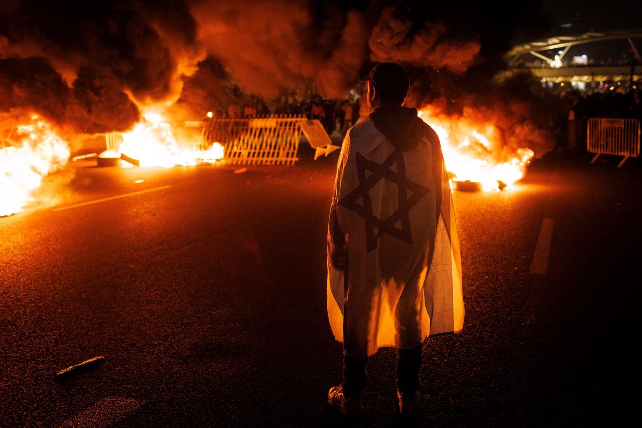 A demonstrator wears an Israeli flag as a road is blocked in Tel Aviv on March 26.