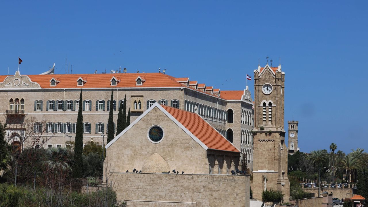 A church's clock tower, front, next to the governmental palace in Beirut indicates the new summer time on March 27, 2023. 