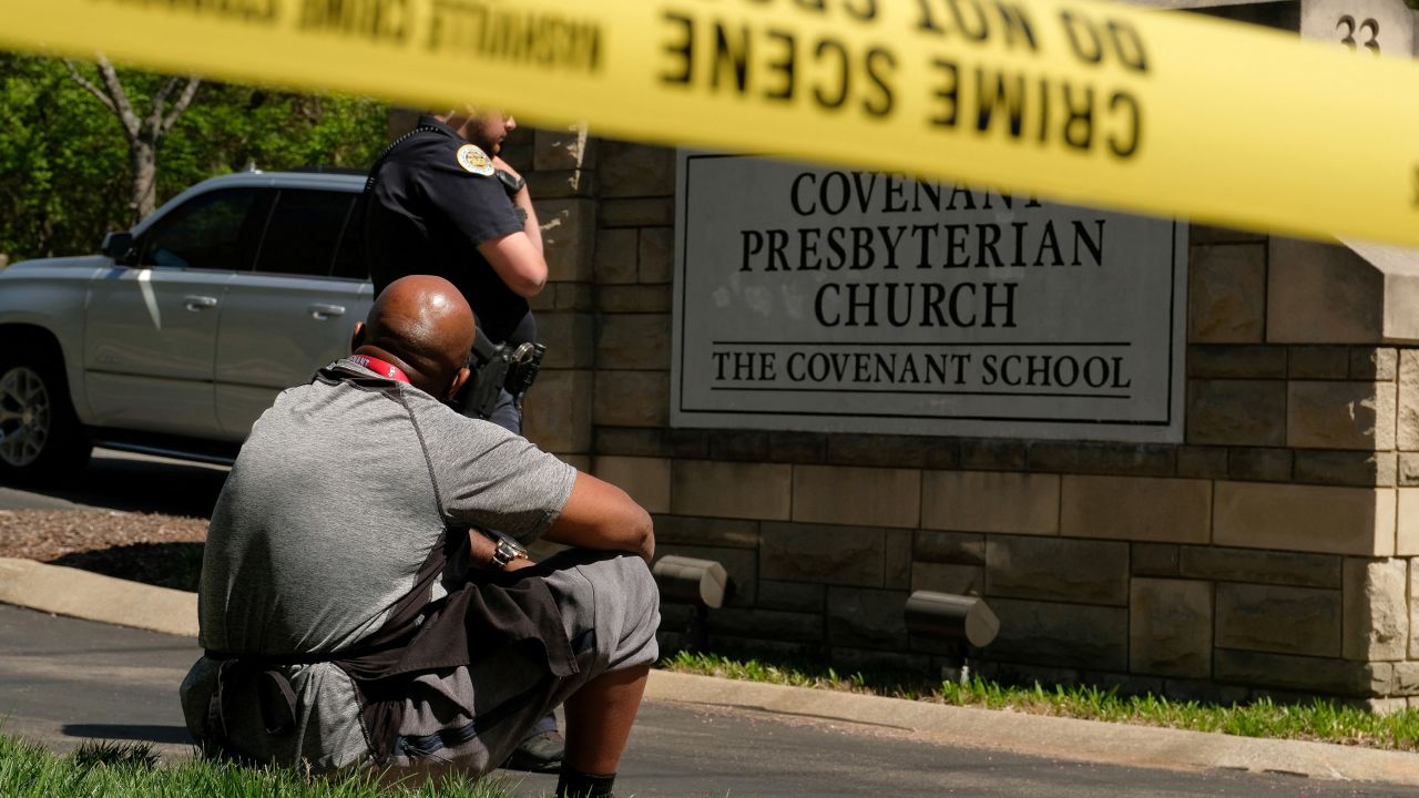 Mario Dennis, one of the kitchen staff at the Covenant School, sits near a police officer after a shooting at the facility in Nashville, Tennessee, on March 27, 2023.
