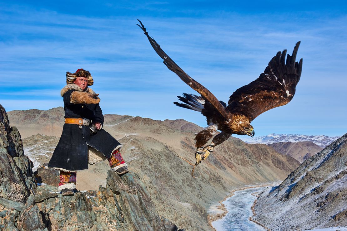 A Mongolian hunter sends his golden eagle to hunt prey.