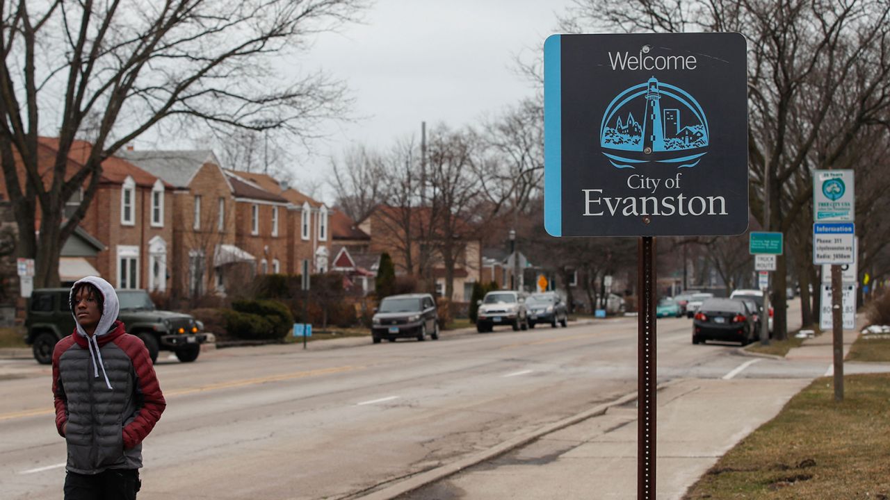 A man walks by a sign welcoming people to the city of in Evanston, Illinois, on March 16, 2021. 