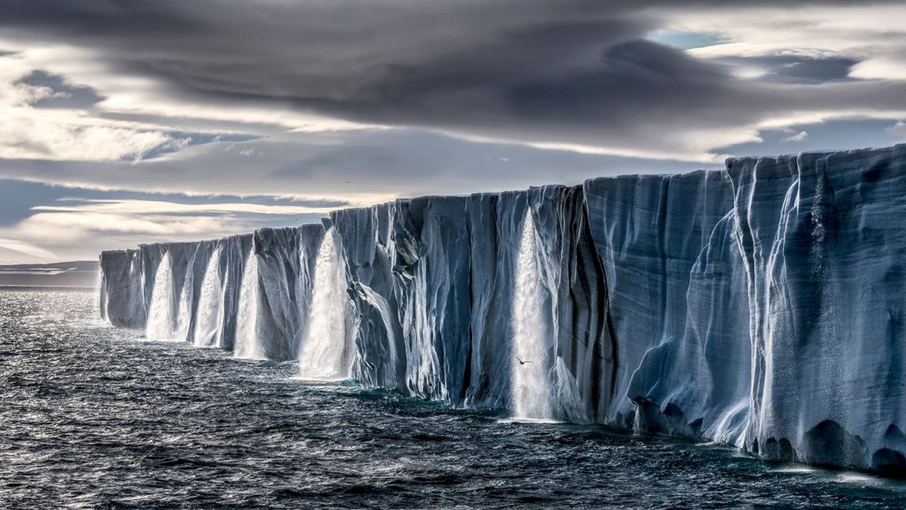 Waterfalls pour off a Nordaustlandet ice cap in Svalbard, Norway, during an unusually warm summer in 2014.  