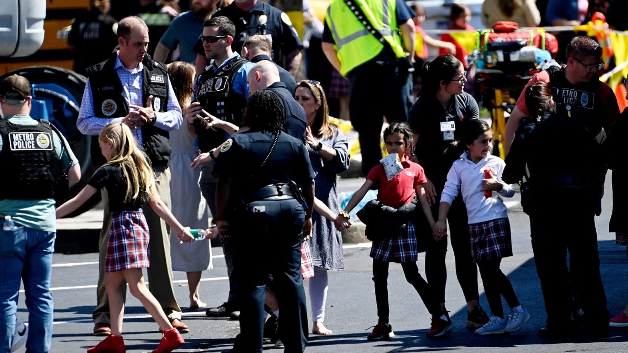 Students from the Covenant School hold hands Monday after getting off a bus to meet their parents at a reunification site after a mass shooting at the school in Nashville.