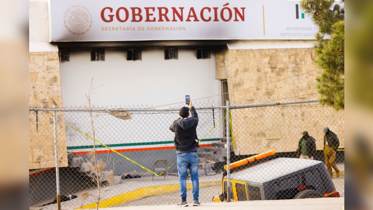 A migrant takes a photo of the blackened INM facility on Tuesday.