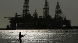 A man wears a face mark as he fishes near docked oil drilling platforms, Friday, May 8, 2020, in Port Aransas, Texas.