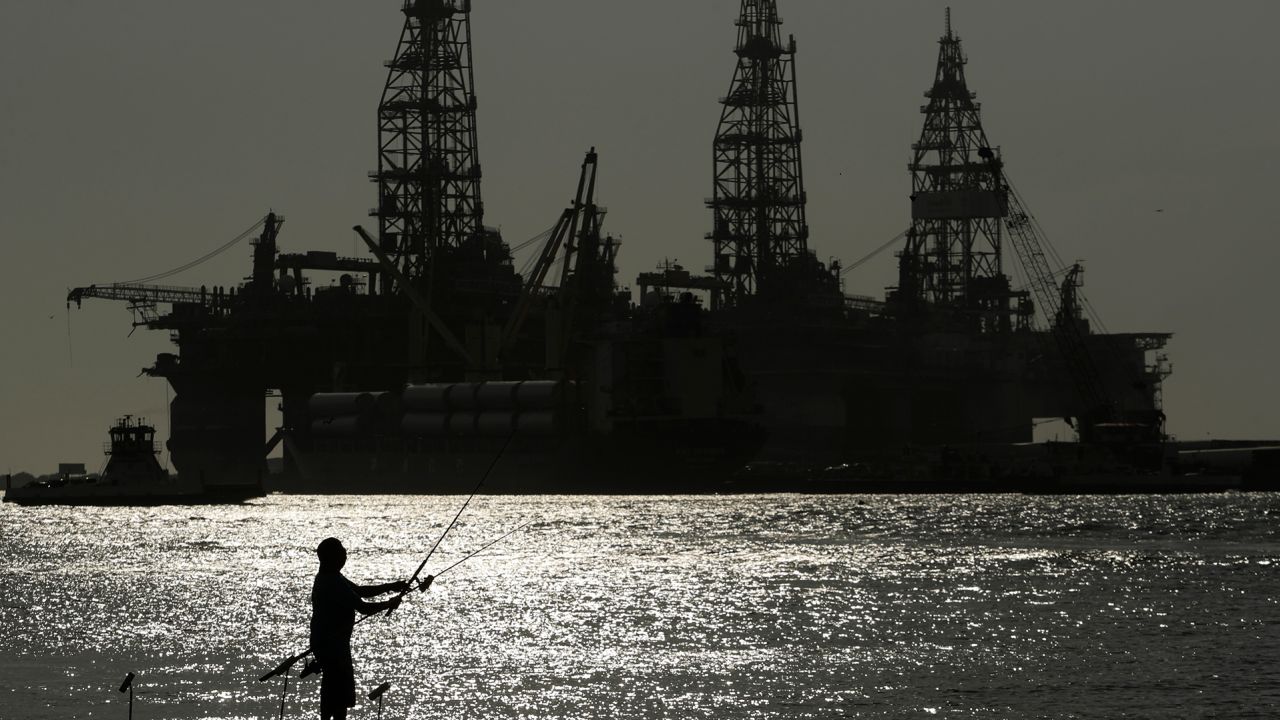 A man fishes near docked oil drilling platforms in Port Aransas, Texas.