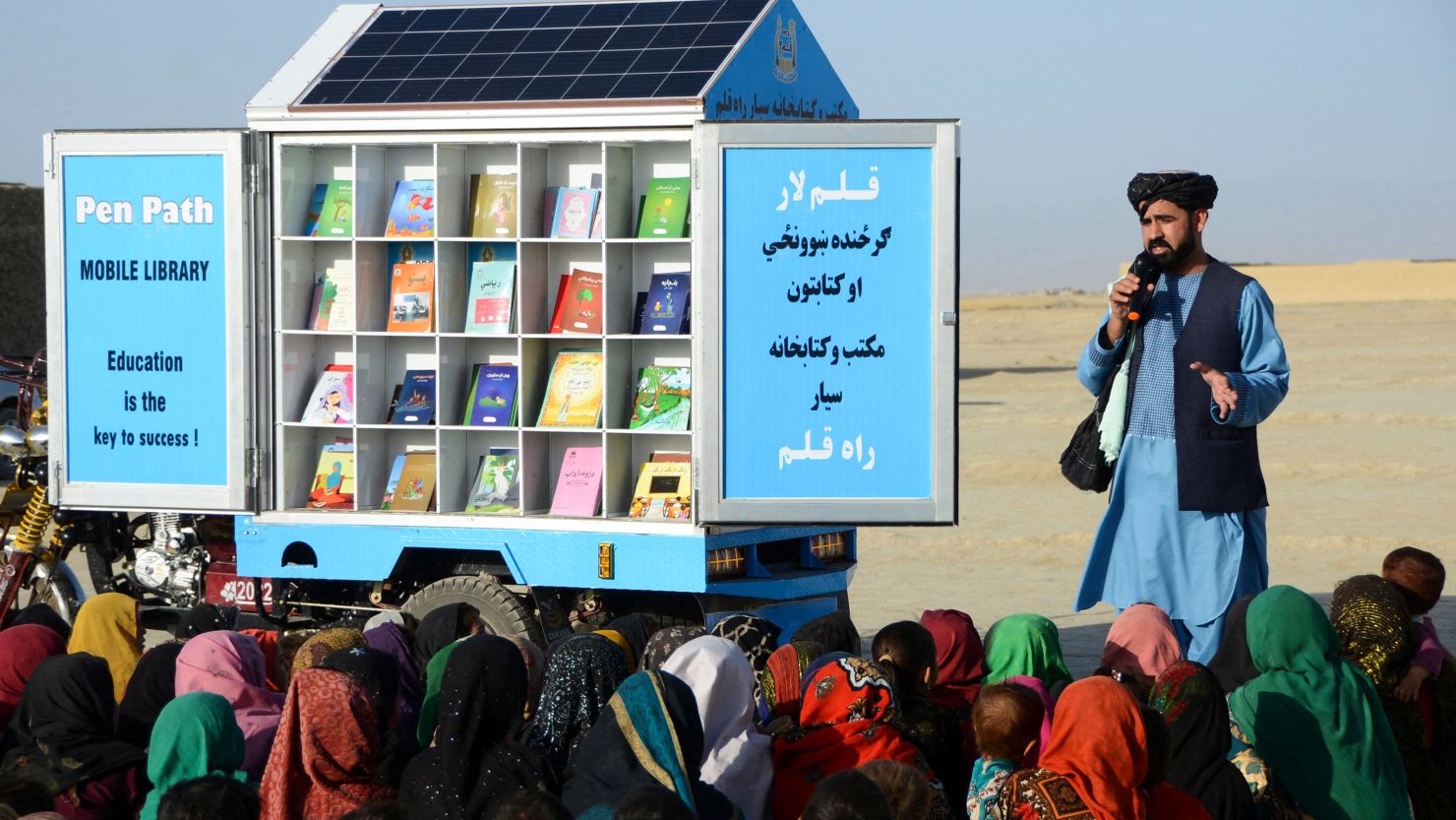 In this photograph taken on May 17, 2022, Matiullah Wesa, head of PenPath and advocate for girls' education in Afghanistan, speaks to children during a class next to his mobile library in Spin Boldak district of Kandahar Province. 