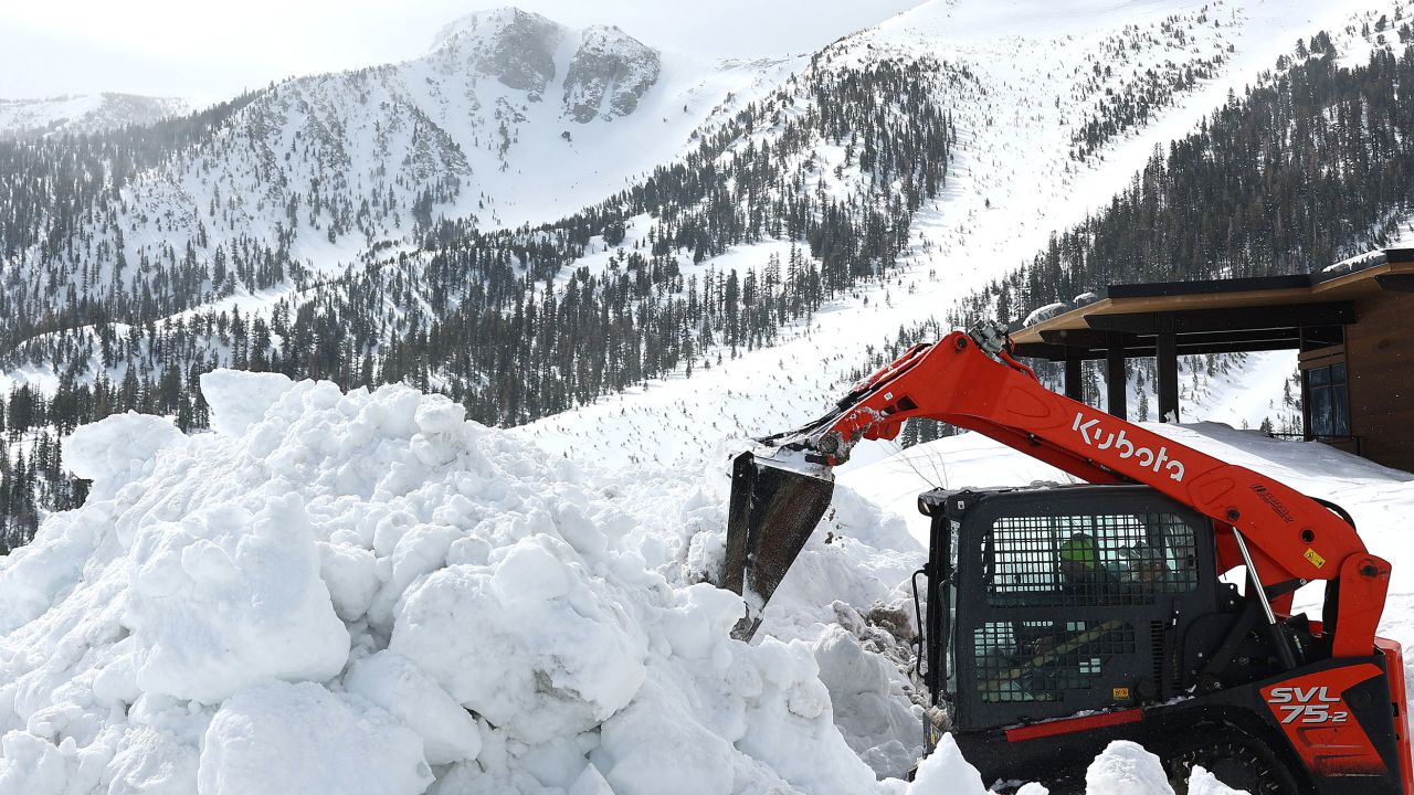A snow removal machine is operated near a snowbank in the Sierra Nevada mountains as yet another storm system arrives Tuesday in Mammoth Lakes, California. 
