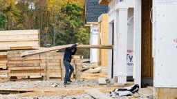 A man carries siding into a house at a new home construction site in Trappe, Maryland, on October 28, 2022.