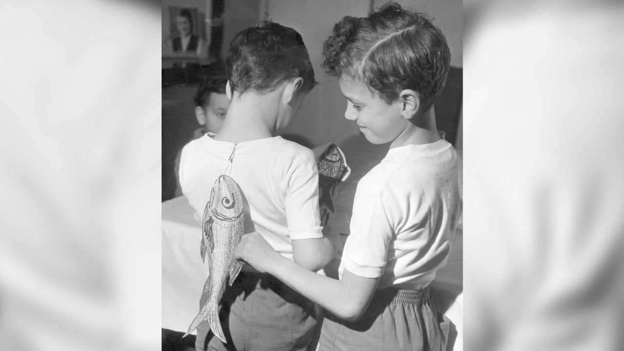 Two brothers sticking April Fools' Day fish on each other's backs on April 1, 1963. 