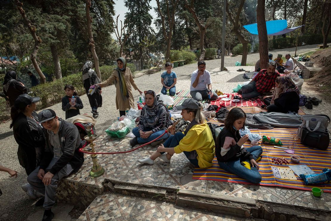 An Iranian young woman puffs on a hookah as she and her family sit together in a park in northern Tehran during the day of Sizdah Bedar, also known as Nature's Day, on April 2, 2022. 