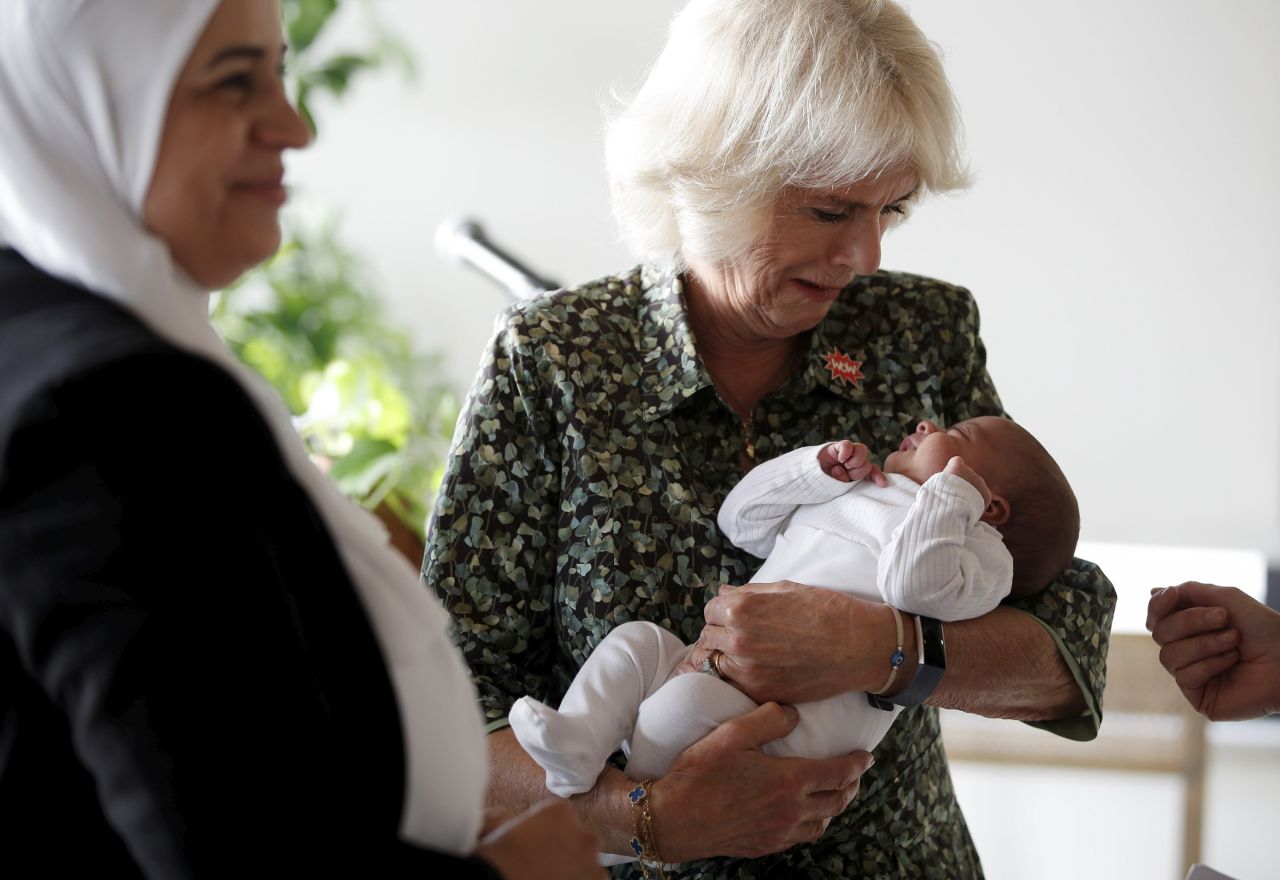 Camilla holds a baby girl while attending a Women of the World Foundation event in Amman, Jordan, in November 2021.