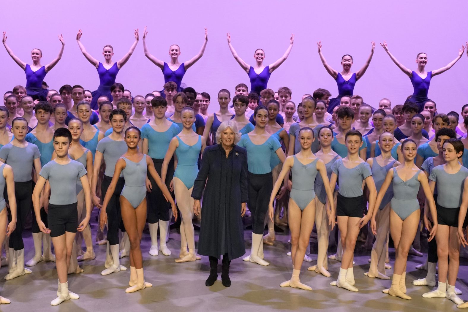 Camilla stands on stage with students during a visit to the Elmhurst Ballet School in Birmingham, England, in March 2023.