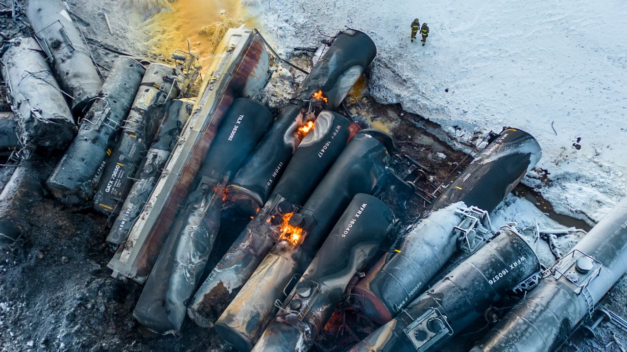 Firefighters stand near piled up train cars, near Raymond on March 30, 2023.