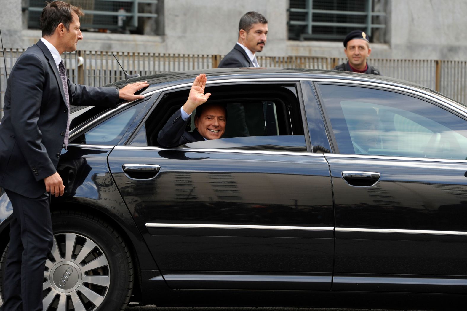 Berlusconi waves as he leaves a court in Milan in September 2011.