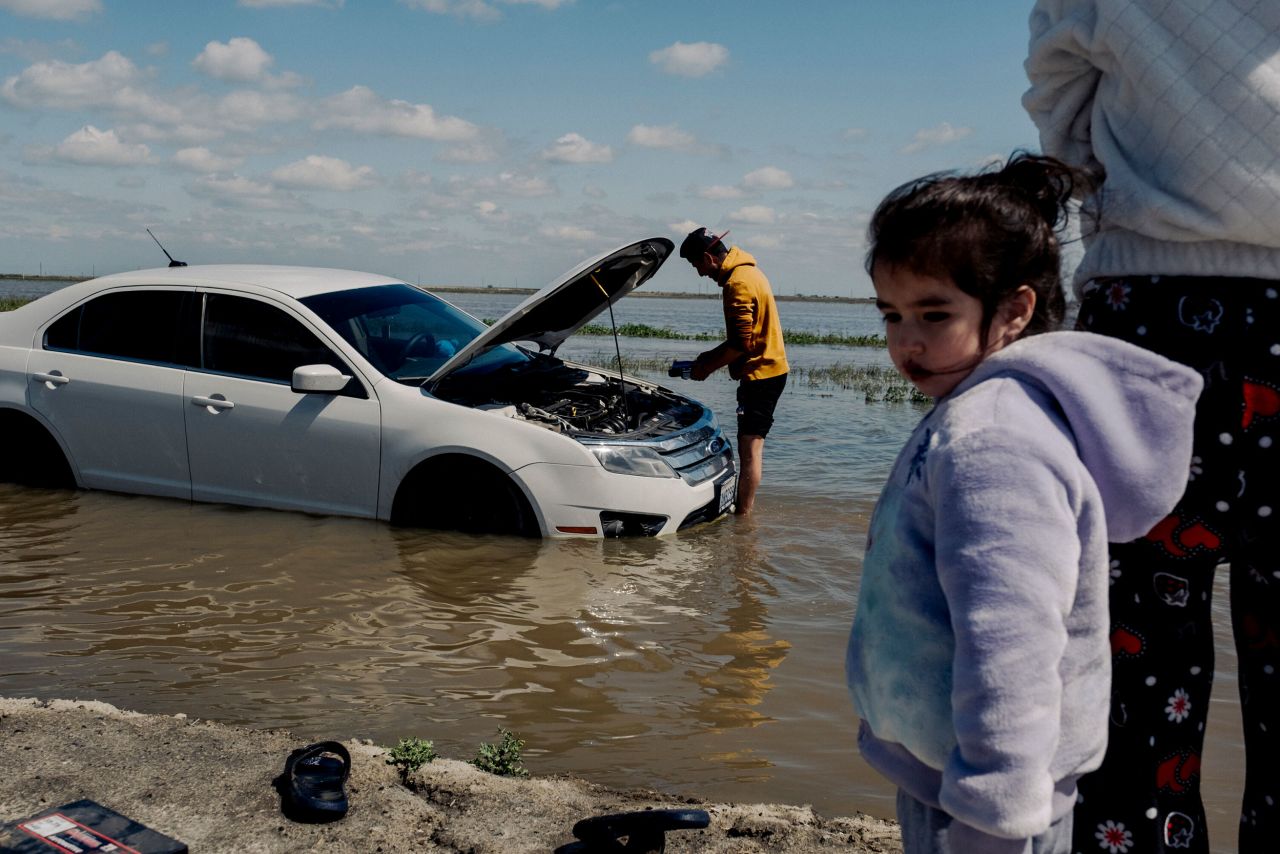 Alfredo Martinez and his family come back to retrieve their car, which Martinez's wife had abandoned after she became stuck in floodwaters near Corcoran, California, on Saturday, March 25.
