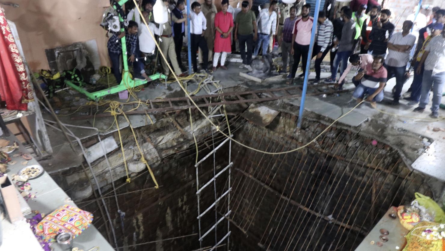 People stand around the collapsed flooring where people fell into a well at a temple in Indore, India, on March 30.