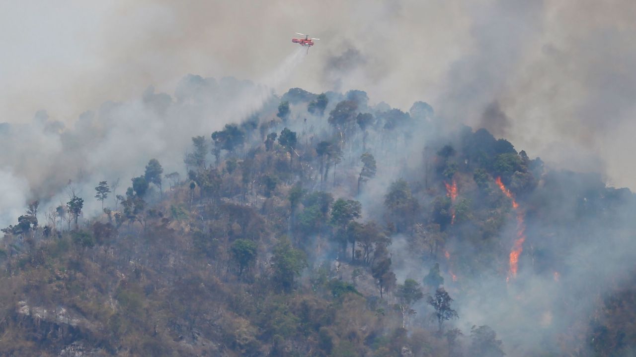 A helicopter drops water over a forest fire hotspot on Khao Laem mountain in Nakhon Nayok province, northeast of Bangkok on March 30.