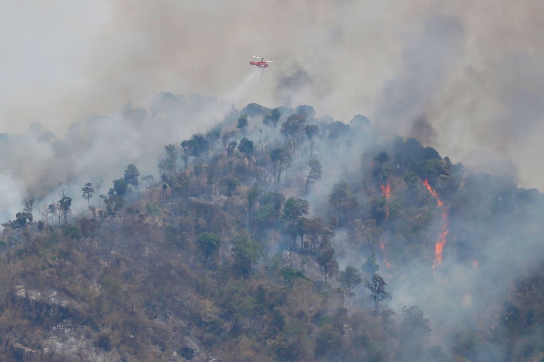 A helicopter drops water over a forest fire hotspot on Khao Laem mountain in Nakhon Nayok province, northeast of Bangkok on March 30.
