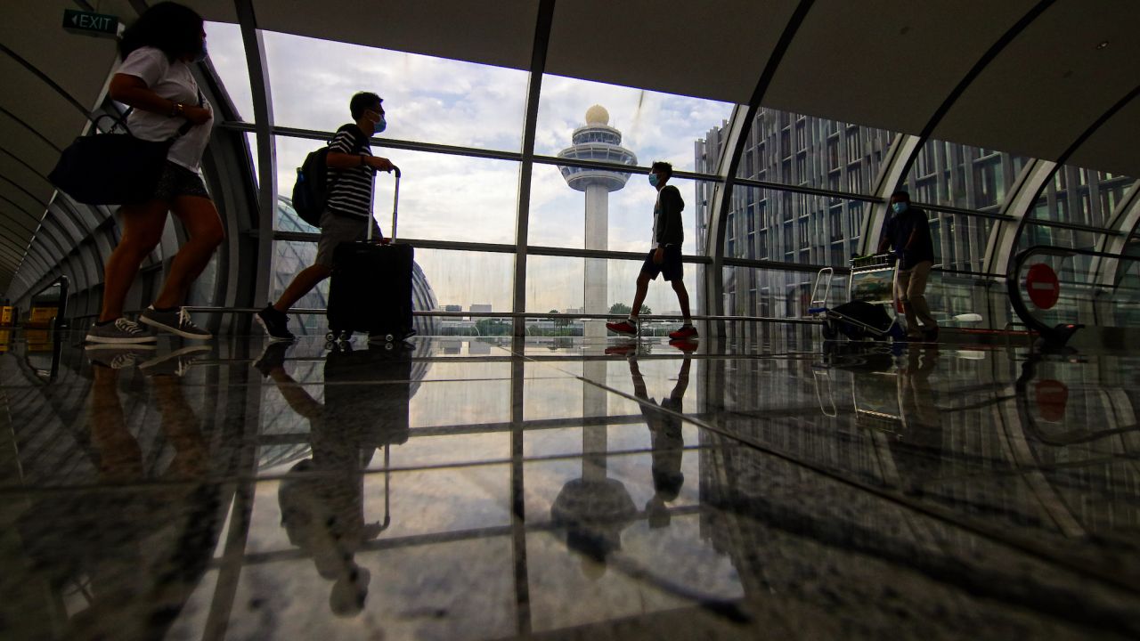 Travelers walk across a bridge linking terminals at Changi International Airport on June 11, 2022 in Singapore.
