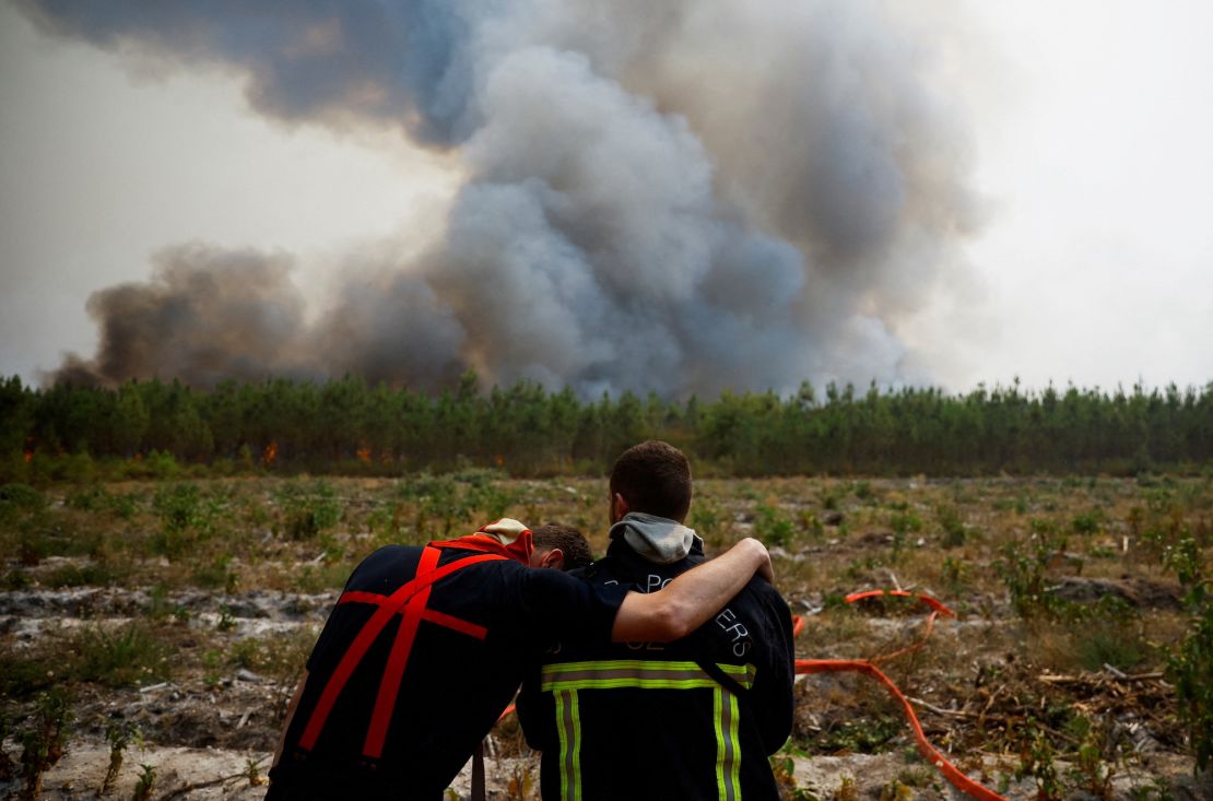 Firefighters embrace as they work to contain a fire in Saint-Magne in southwest France in August 2022.