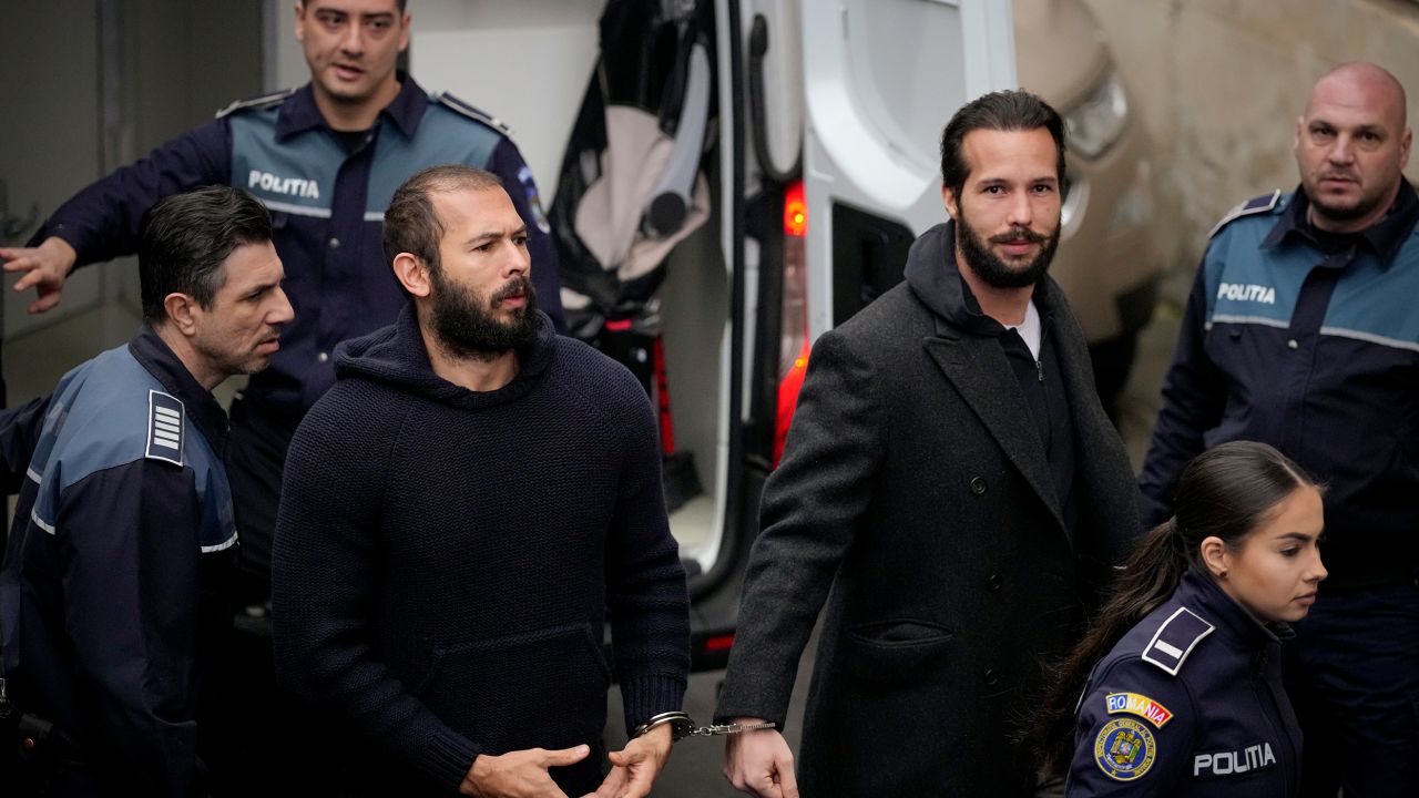 Police officers escort Andrew Tate, center, handcuffed to his brother Tristan Tate, to the Court of Appeal in Bucharest, Romania, Monday, Feb. 27, 2023. 