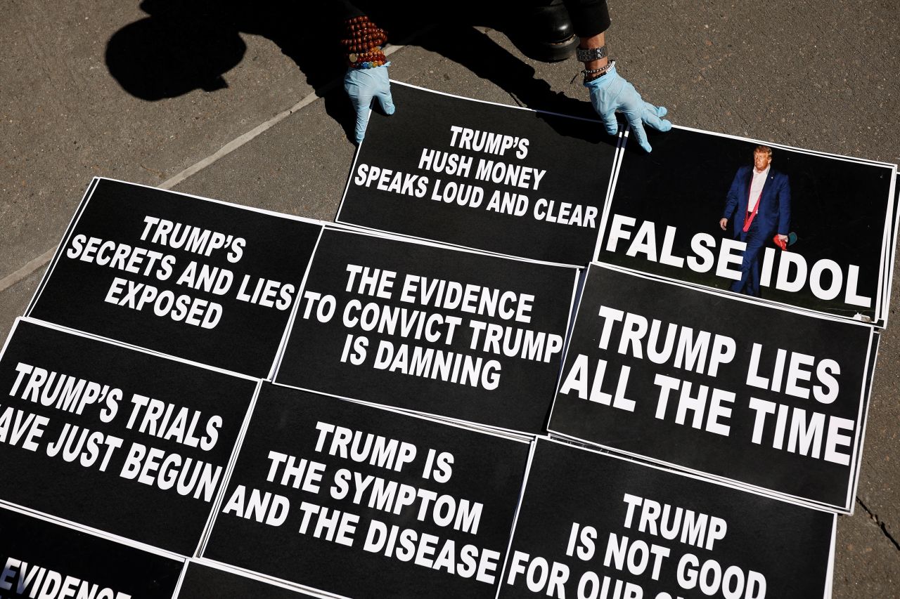 A person places signs on the ground as anti-Trump protesters gathered outside the Manhattan Criminal Courthouse on Monday, March 27.