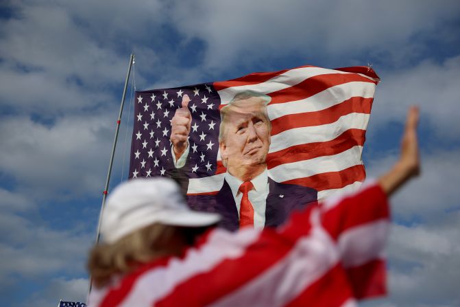 Evelyn Knapp walks past a Trump flag that his supporters were flying near his Mar-a-Lago home on March 20, 2023.