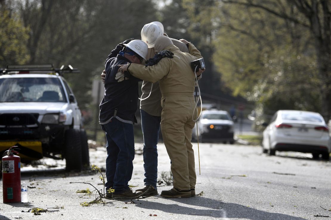 A team from Summit Energy say a prayer together before investigating a burst gas line in Cammack Village, Arkansas, near Little Rock, after a tornado swept through the area on Friday, March 31.